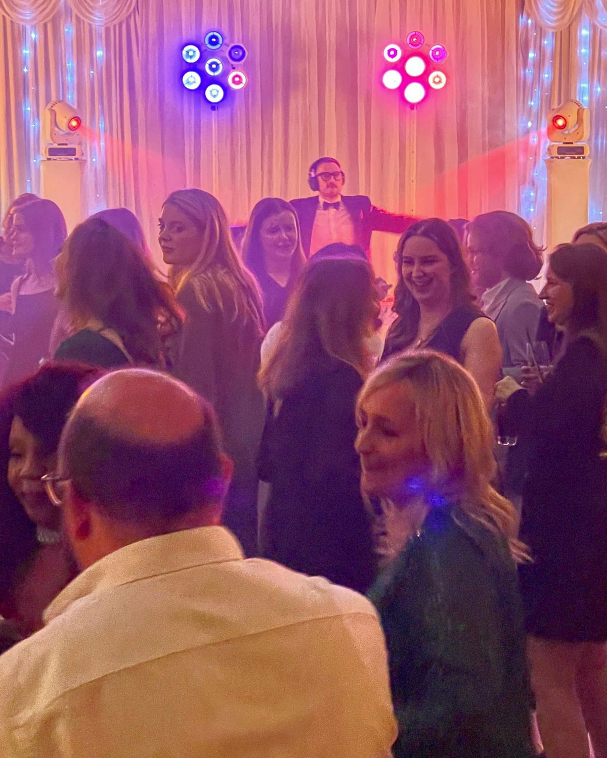 A full dance floor with the DJ working the room from the booth behind