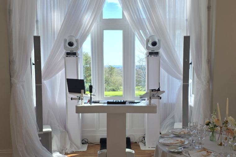DJ booth in the draped bay window at Highley Manor, beside a laid top table, looking out over the grounds