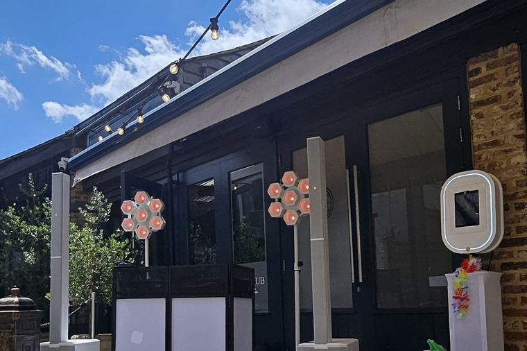 DJ booth and speakers set up outside in the courtyard at The Hub on Verulam under festoon lights and blue sky