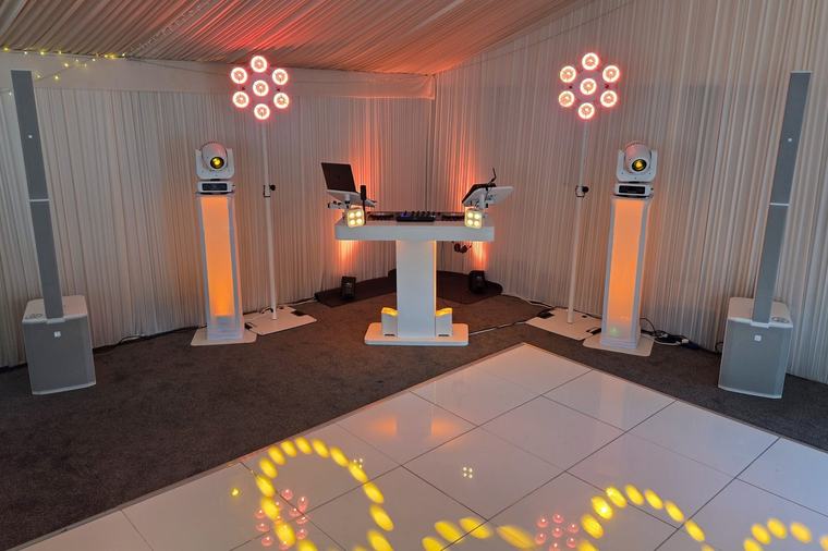 DJ booth, speakers and moving lights in the marquee at Hunton Park beside a white dance floor