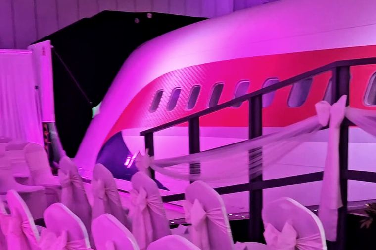The pink-lit aeroplane fuselage at Manchester Barton Aerodrome, with rows of sashed chairs set out in front of it