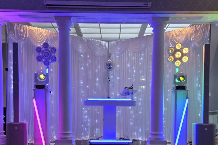 DJ booth between white pillars and draped starlight backdrop at Normanton Park Hotel, with gobos on the dance floor