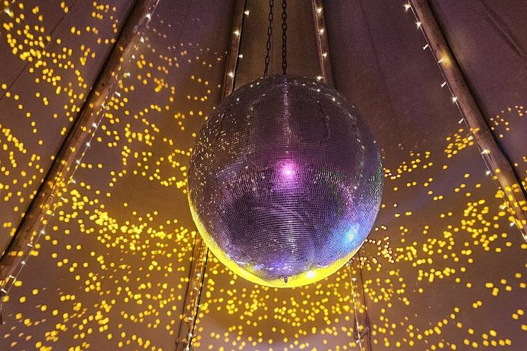 A large mirror ball hanging in the tipi at Whatton House, scattering light across the canvas